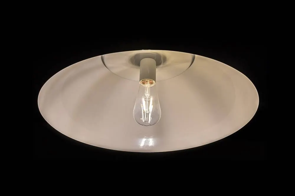Suspension blanche avec ampoule à filament allumée sur fond noir