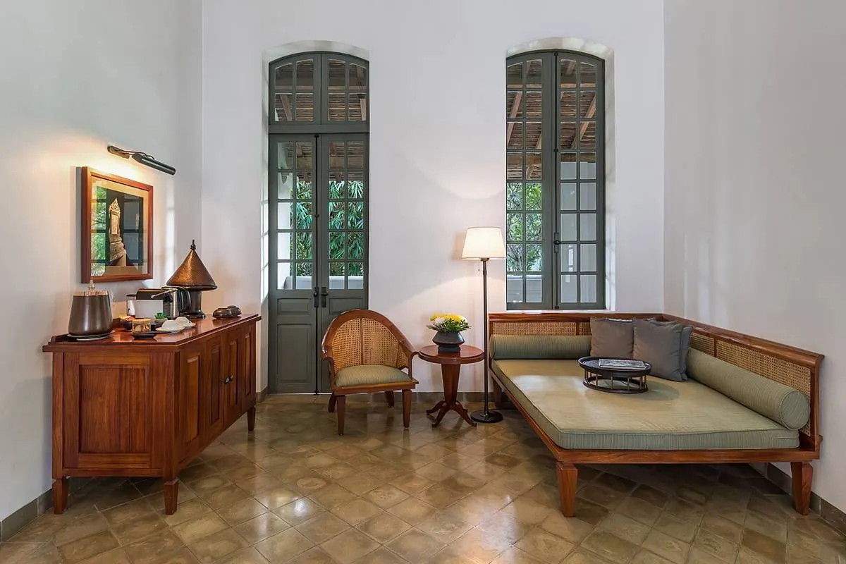 Salon épuré : lit de repos, enfilade en bois, lampadaire et hautes portes-fenêtres