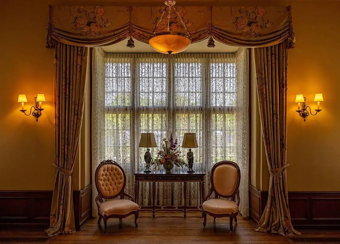 Deux fauteuils face à une grande fenêtre, lumière chaude des appliques
