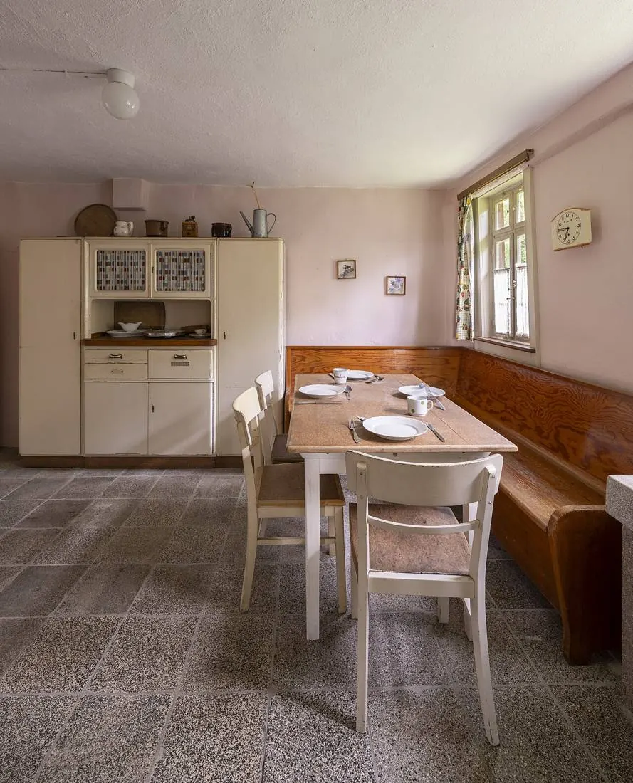 Cuisine sobre avec banquette d'angle, table blanche et vaisselier