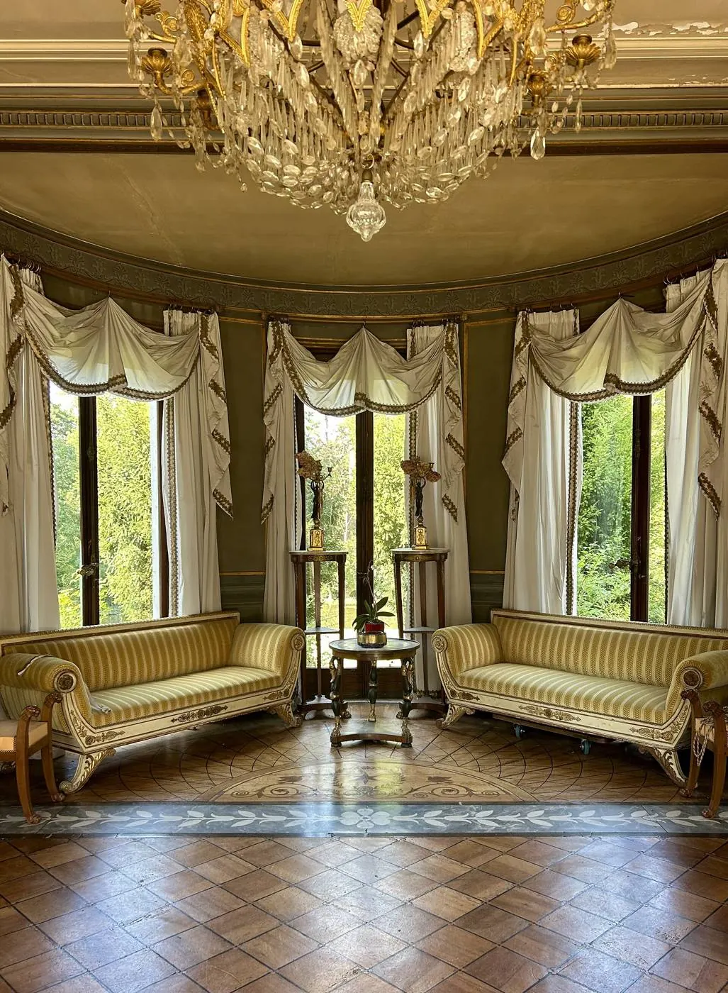 Salon ancien lumineux, hautes fenêtres, parquet en point de Hongrie et deux canapés rayés